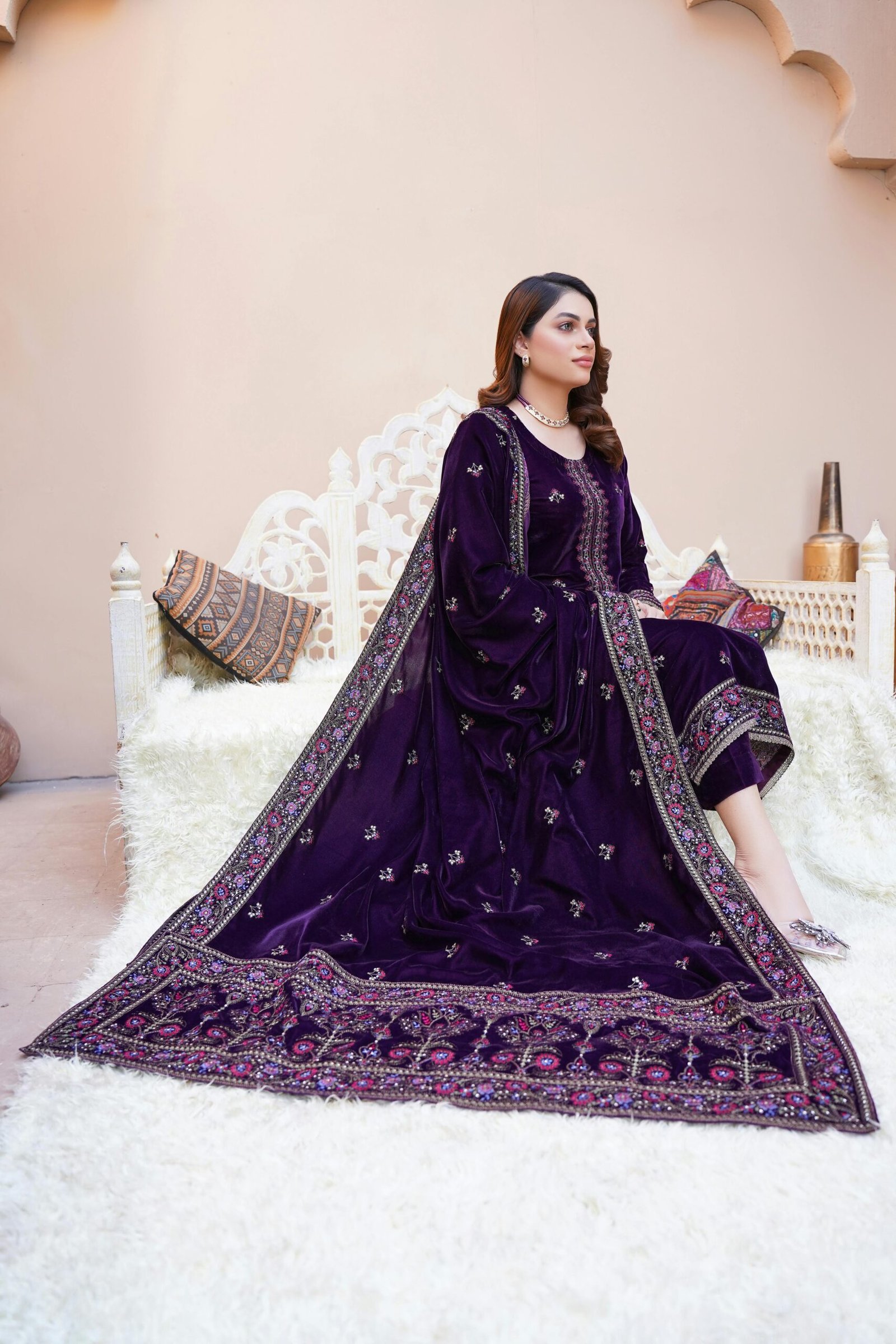 Stylish model in a luxurious purple velvet dress sitting elegantly in Lahore.